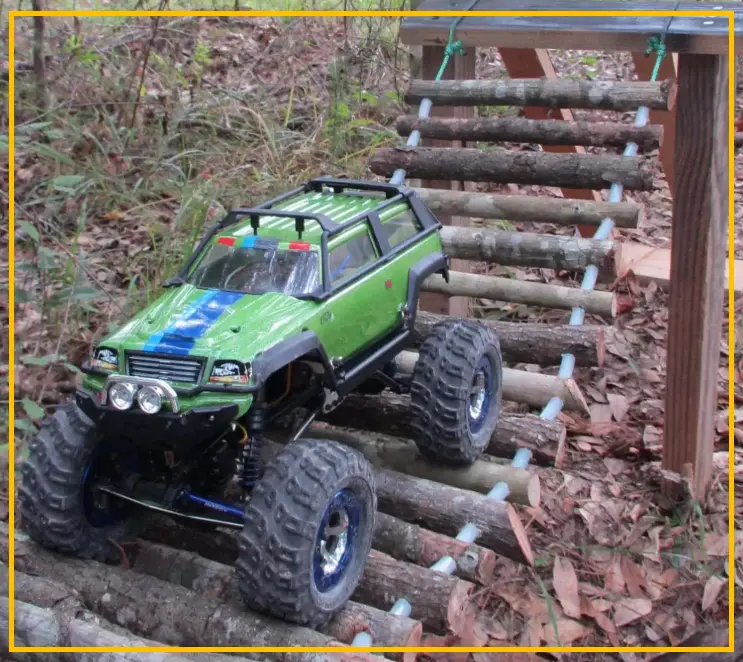 An RC rock crawler navigating a narrow gap between rocks on a small backyard course