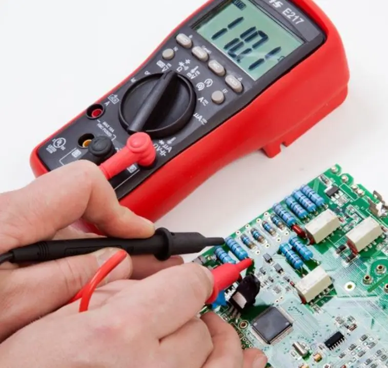 Digital multimeter probes checking continuity between the positive and negative power pads of an FPV drone