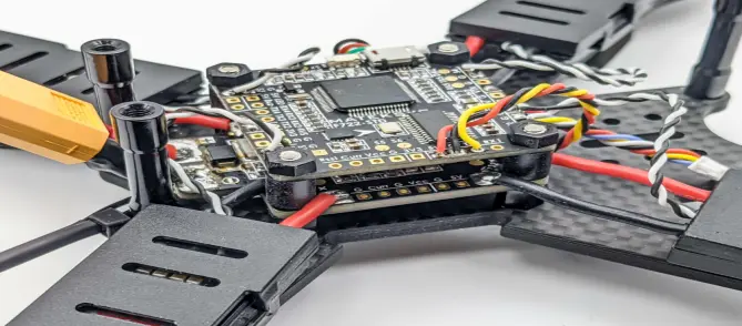 FPV drone resting on a level workbench with its flight controller visible