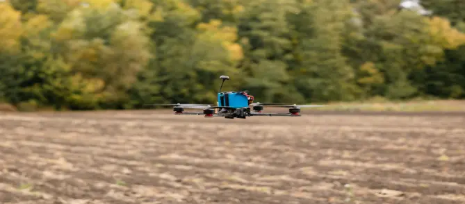 FPV quadcopter flying steadily over an open field