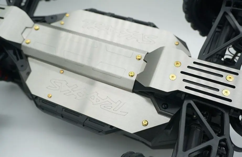 Metal skid plate protecting the underside of an RC off-road truck chassis